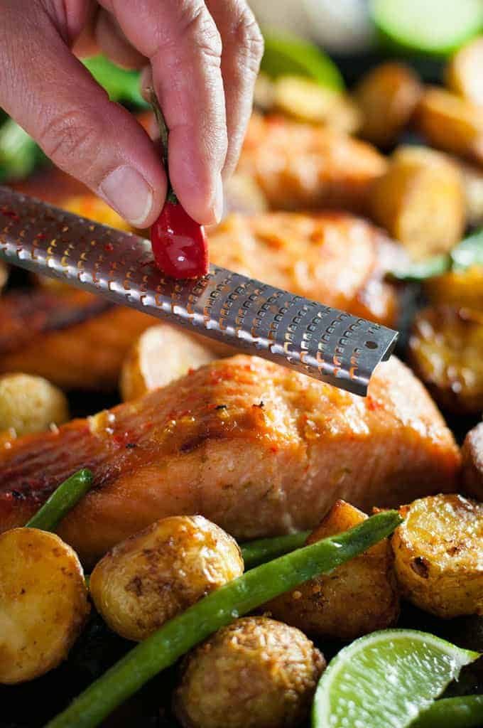 Grating chilli over Chili Lime Baked Salmon with Potatoes and Beans (One Tray Meal)