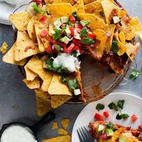 Nachos Pie topped with salsa, served with extra sour cream