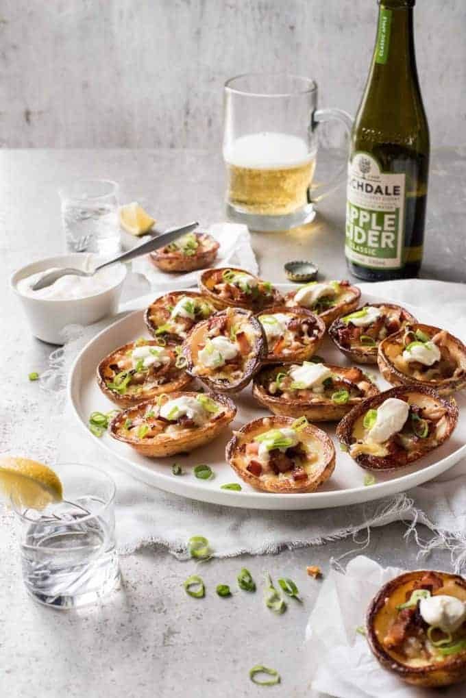 A platter of Cheese & Bacon Potato Skins with bottle and glass of cider