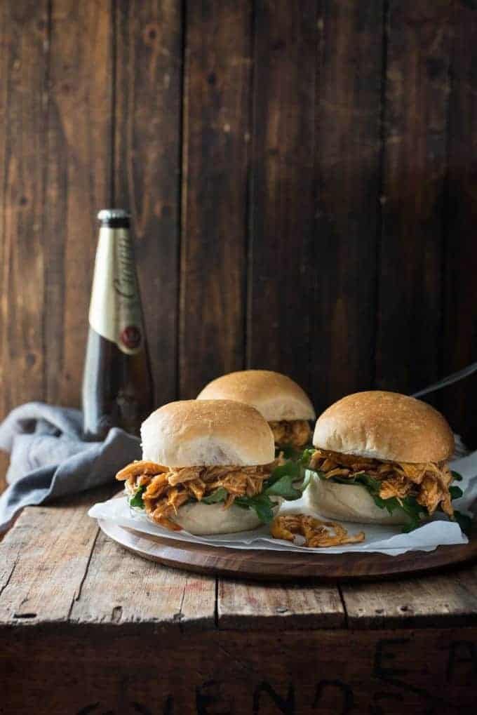 Slow Cooker Honey Buffalo Chicken Sliders on a platter with beer