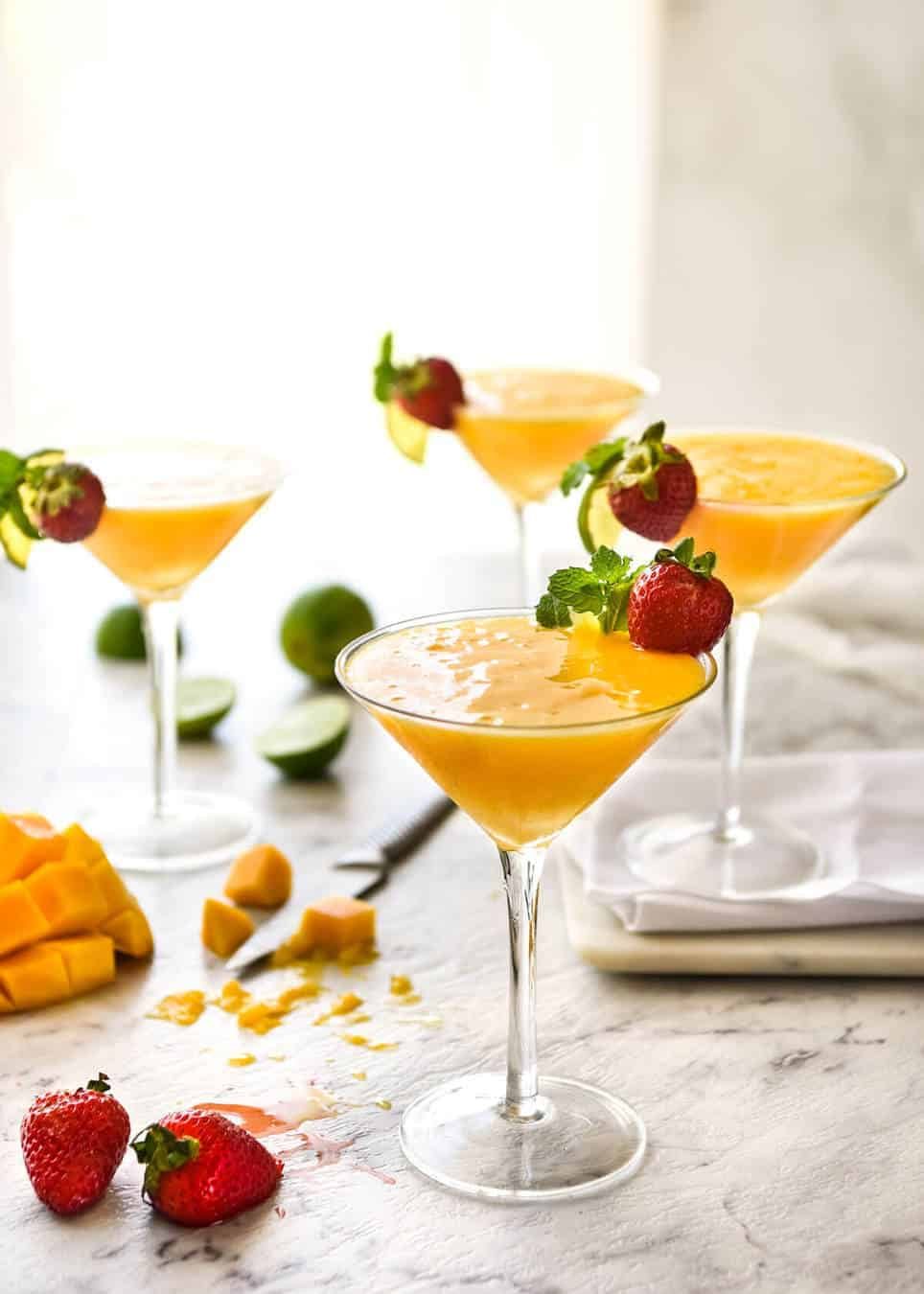 Frozen Mango Daquiris in cocktail glasses, garnished with strawberries.