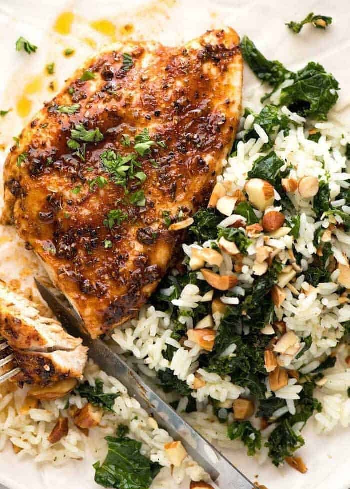 Baked Chicken Breast with a side of Garlic Butter Rice with Kale on a white plate, ready to be eaten.