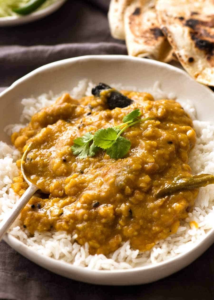 Homemade India lentil curry (Dal) served over rice in a rustic white bowl, ready to be eaten.