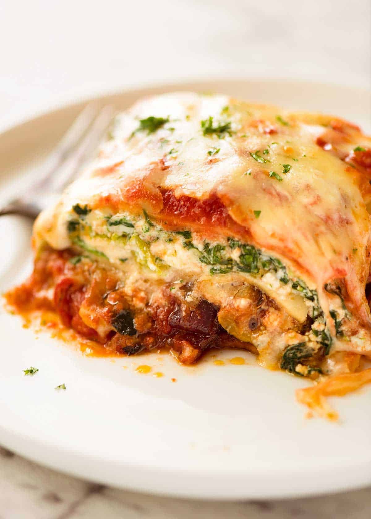 Close up of a slice of Vegetable Lasagna on a white plate, ready to be eaten