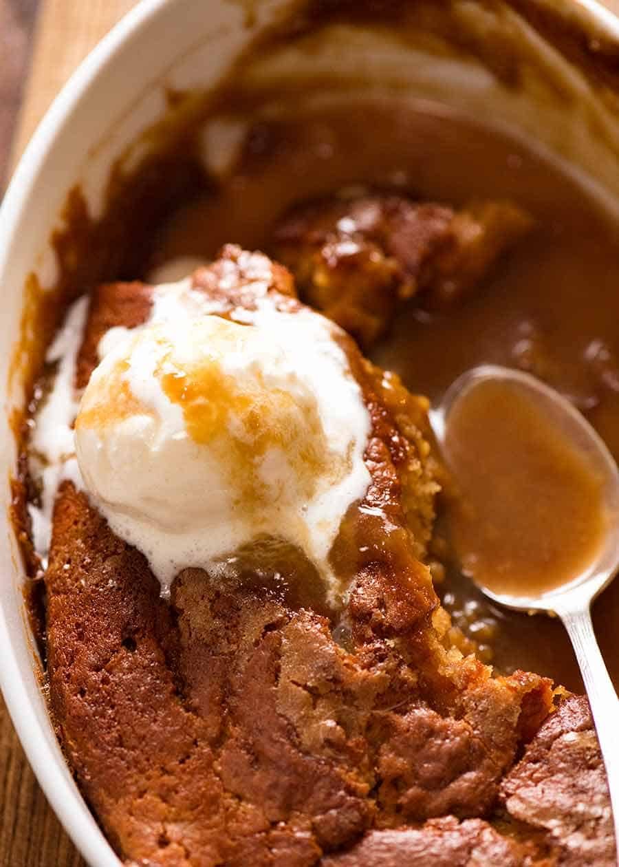 Close up of Self Saucing Butterscotch Pudding in baking dish, being served