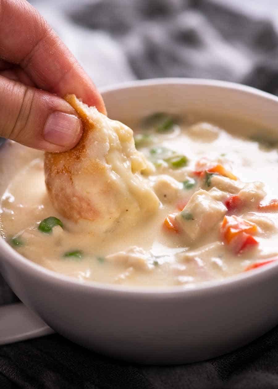 Close up of dunking bread into healthy Cream of Chicken Soup