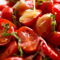 Dressing being poured over Tomato Salad