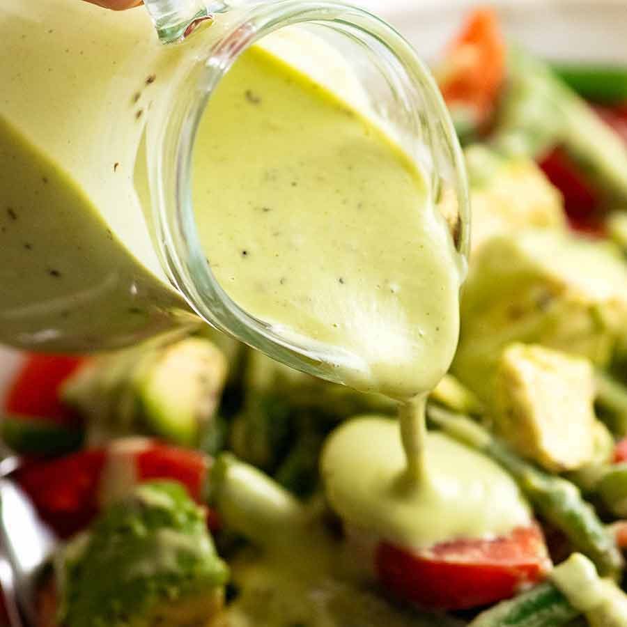 Pouring Creamy Avocado Dressing over green bean salad