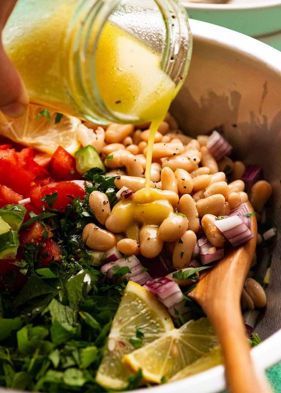 Pouring lemon dressing over White Bean Tabbouleh Salad