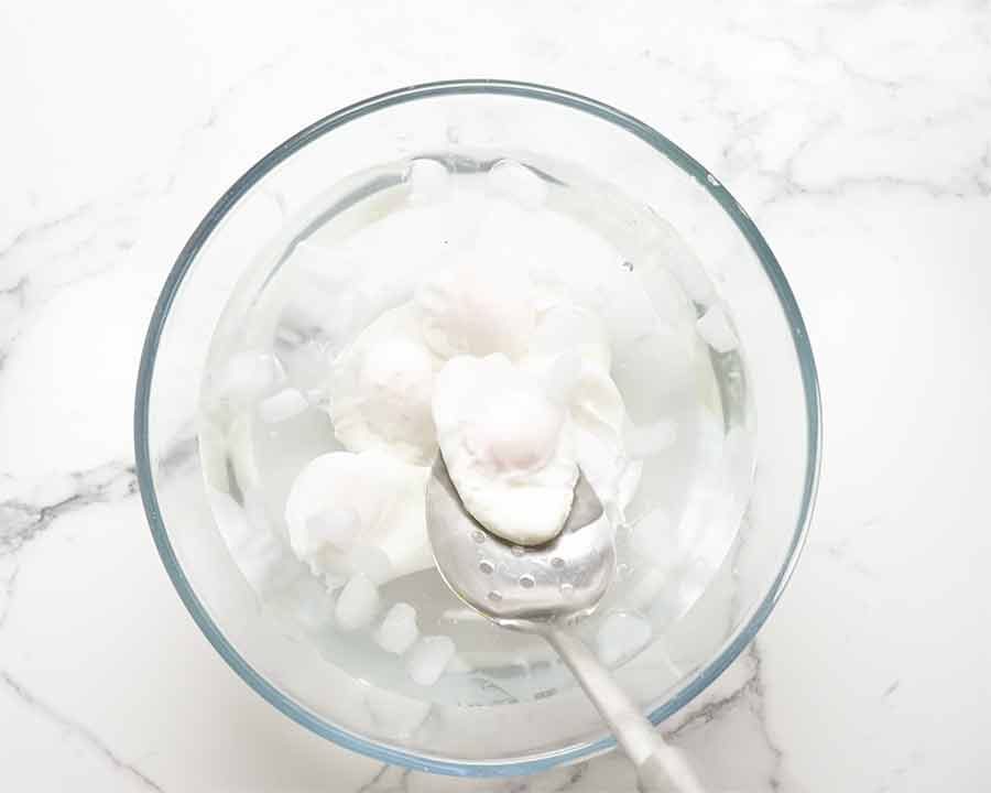 Putting cooked poached eggs in cold water