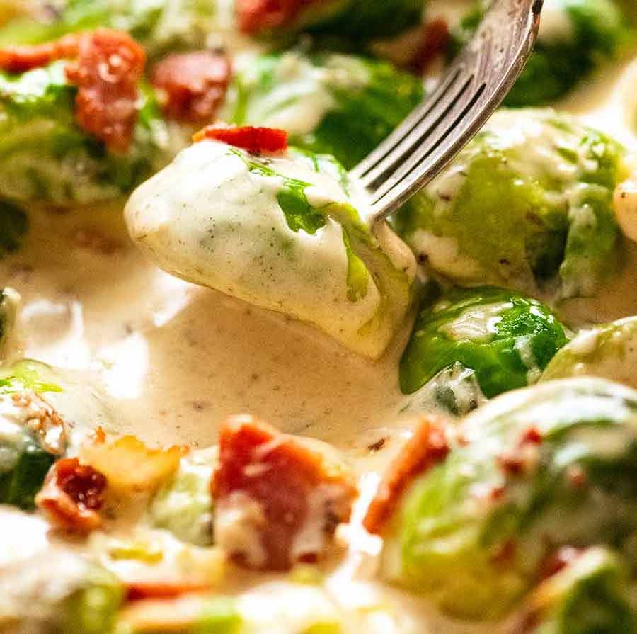 Fork picking up sautéed Brussels sprouts in a creamy sauce