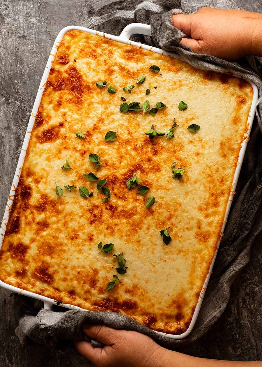 Freshly baked Pastitsio being placed on a table, ready to be served (Greek beef pasta bake)